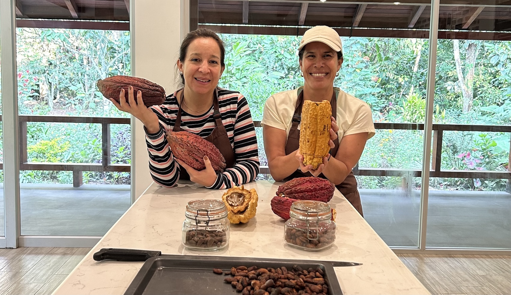 two women holding cacao fruit at a kitchen table in Amazon