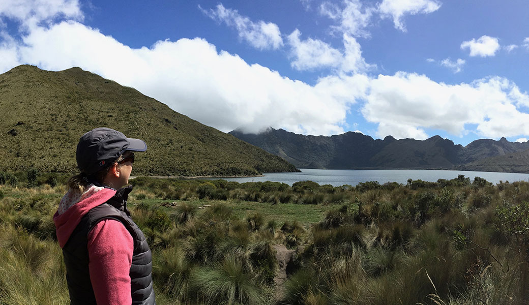 Lady in pink jacket and baseball hat looking at Mojanda Lake In Ecuadorian Andes